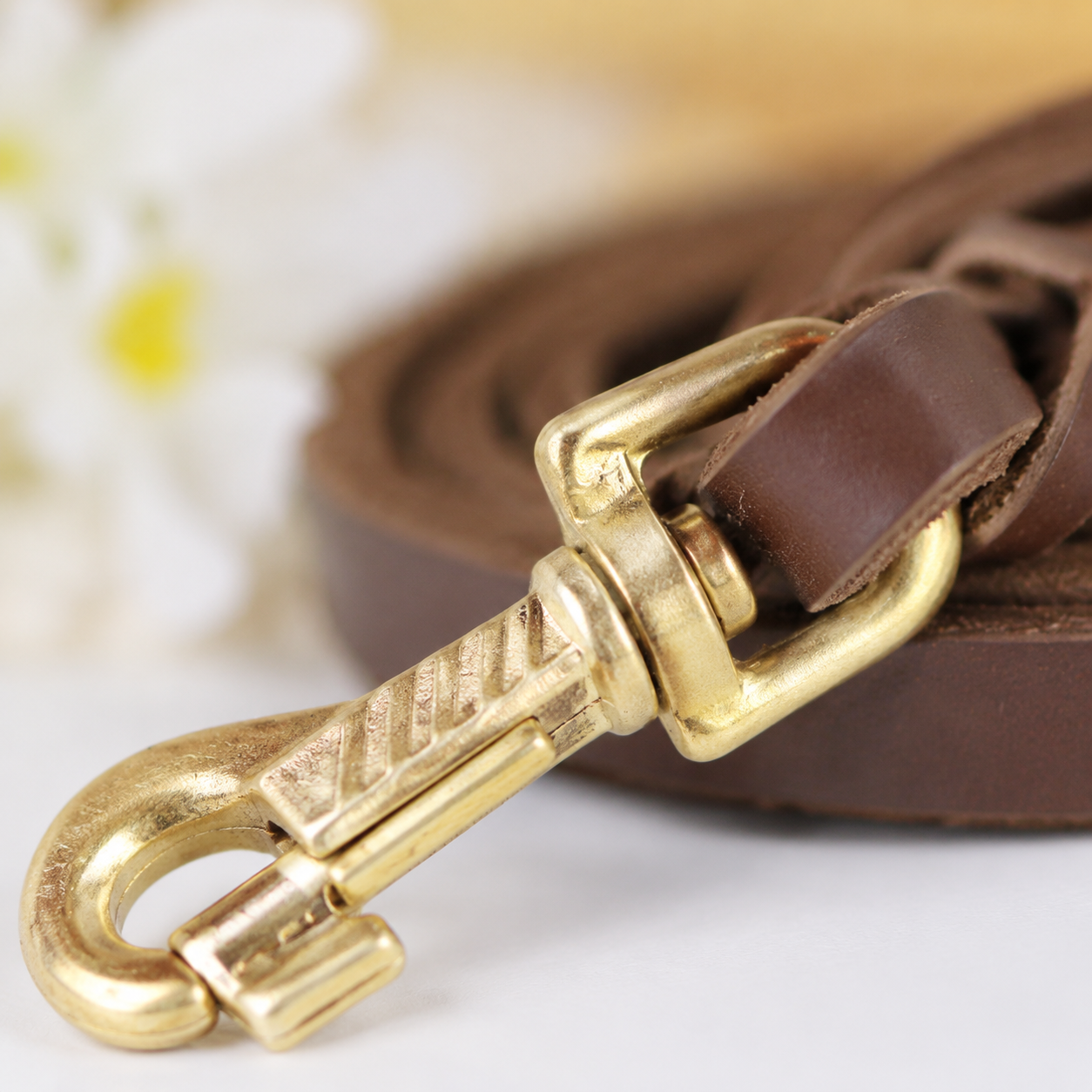 Close-up of solid antique brass buckle and interwoven leather transition on brown leather dog leash